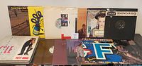 Full lot of approximately 25 mixed vinyl records including singles and EPs displayed in multiple rows showing spines and front covers.