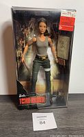 Front view of the boxed Barbie Signature Tomb Raider Lara Croft action figure with knife accessory and green pants outfit.