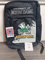 Front view of the black vintage University of Notre Dame backpack showing official U.S. College licensed tag, Fighting Irish mascot graphic, and text.