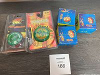 Photo of five yo-yos showing two in blister packs and three boxed or loose between them, including a Fireball yo-yo in original packaging.