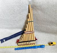 Wooden pan flute, blue plastic recorder, and measuring tape to show size