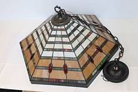 Side angle showing the stained glass panels with amber, white, green, and red pieces and the metal chain for hanging.