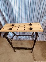 Full view of Ultra Workmate-style folding workbench with wooden slat work surface and black metal frame.