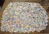 Top-down photo showing a very large spread of mixed world postage stamps, mostly loose and some on paper, displaying various colors and designs.