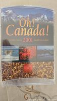 Front view of unopened 2001 Oh! Canada! coin set package with images of Canadian nature scenes and text.