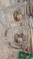 Photo of two mini clear glass A&W Grandpa Burger collectible glasses with printed logos.