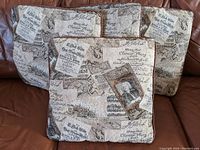 Four square cushions featuring print designs related to Johann Sebastian Bach, with visible musical notation and a portrait, brown edge trim.