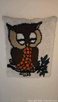 Full front view of a handmade tufted rug showing a brown owl with cream eyes and orange belly on a cream background.