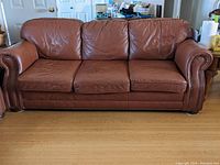 Front view of three-seat leather sofa couch light coffee brown with slight scratches and surface wear.