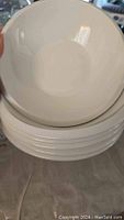 Stack of six white ceramic salad bowls with glossy finish, showing shape and size.