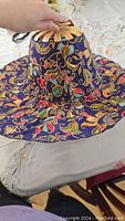 Hat fully opened showing wide brim and colorful floral fabric with bamboo frame