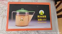 Boxed oil container with green lid, clear plastic body, and handle visible on box image.