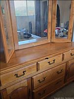View of dresser surface and large central mirror with side folding mirror panels open