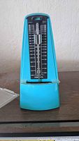 Blue Nikko mechanical metronome without cover on a brown surface