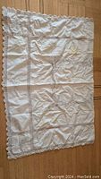 Full view of vintage light cream tablecloth laid flat showing lace borders and inserts.