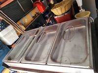 Top view of the food warmer showing four stainless steel food compartments with lids and handles.