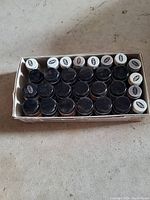 Box containing 29 small bottles of Model Master enamel paint with black and white lids.