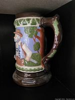 Front view of a ceramic beer stein decorated with a colorful hunting scene featuring a hunter and woodland background.