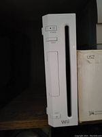 Front view of a white Nintendo Wii console showing the disc slot, power, reset and eject buttons, and Wii branding.
