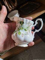 Close-up photo of Royal Albert floral patterned creamer showing fluted body, ornate handle, and gold rim.