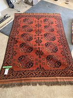 Full view of rust orange rug with repeating navy and teal geometric medallions laid flat on floor