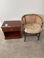 Full view of the vintage woven back barley twist arm chair with floral seat cushion alongside the small wooden end table.