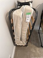 Folded folding bed with white textured foam mattress secured inside the metal frame, ready for storage or transport.