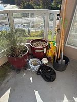 Full lot view showing two large clay pots, smaller decorative pots, tools, soil and more outdoors