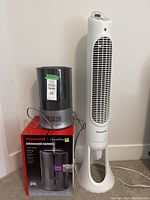 Honeywell designer series cool mist humidifier on box and white tower fan side by side