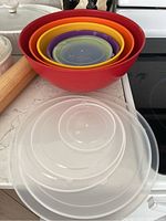 Photo of stacked colorful plastic mixing bowls with matching lids on counter
