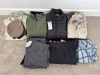 Full lot view showing all clothing items: multiple jackets, vests, shirts, pants, and one hat.