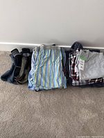 Photo showing men's socks, striped pajama pants, and folded pajama shirts with tags.