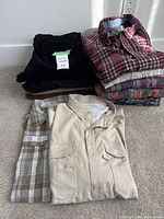 Photo of stacked men's corduroy pants and flannel shirts including a beige Columbia shirt and plaid shirts.
