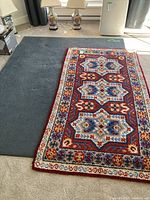 Both rugs overlapped on floor showing patterned rug atop solid blue rug