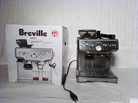 Front view of Breville espresso machine alongside its original box