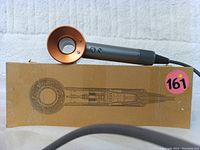 Side view of Dyson Supersonic hair dryer resting on original shipping box