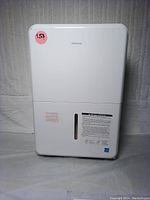 Front view of white Insignia dehumidifier showing water level window and model branding.