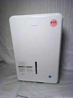 Front view of white Insignia dehumidifier showing model and water level window on water tank section