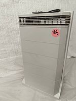 Front view of white rectangular IQAir HealthPro Plus air purifier showing vented area and power cord on top.