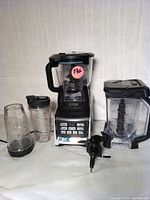 Front view of Nutri Ninja blender base with large blending pitcher and multiple blending cups and blades