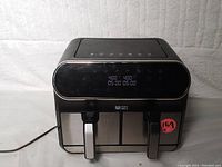 Front view of Ultima Cosa Presto dual basket air fryer showing digital control panel and dual baskets with handles.