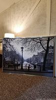 Front view of black and white framed print showing Amsterdam canal scene with bicycle and lamppost.