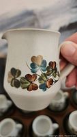 Close-up of cream pitcher showing hand-painted shamrock design and texture of the stoneware