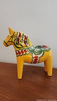 Front side view of the yellow horse figurine showing detailed hand painted multi-colored decorations.