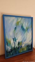 Original framed oil painting with blue frame showing abstract rain scene in blues, greens, and whites