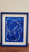 Frontal image showing entire framed artwork with blue frame, white mat and abstract nude figure in blue and white.