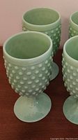 Close-up view of four hobnail patterned vintage green goblets showing texture and color