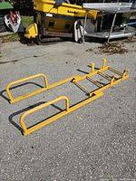 Yellow loading dock ladder with two handrails set on pavement outside, showing full length and structure.