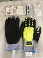 Pair of MAPA gloves lying flat, right glove showing palm coated in black, left glove showing yellow knuckle protection and blue cuff.