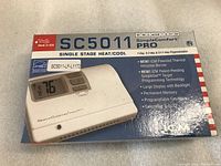 Photo shows ICM Controls SC5011 SimpleComfort PRO thermostat box front with product image and features in English.